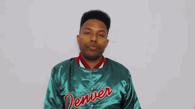 a man wearing a green denver jacket holds his arm up