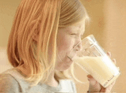 a young girl drinking a glass of milk with a straw