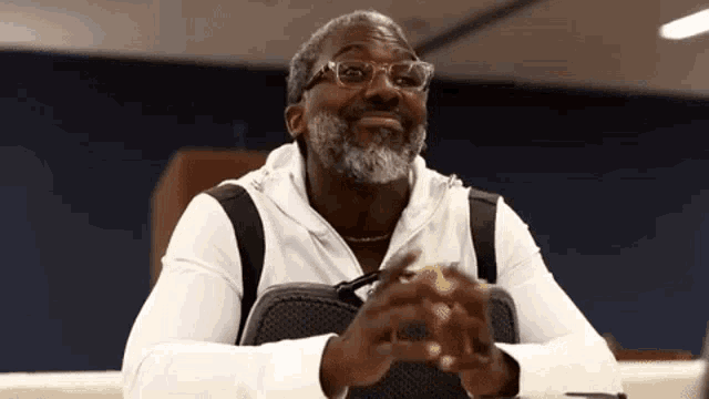 a man with a beard and glasses is sitting at a table .
