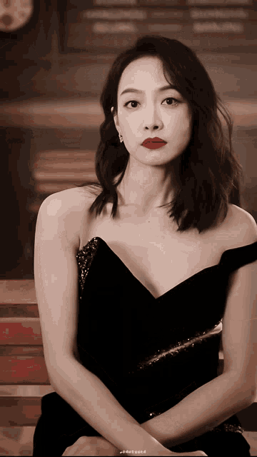 a woman wearing a black dress with red lipstick is sitting on a bench