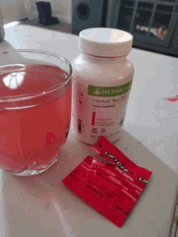 a bottle of herbalife herbal tea next to a cup