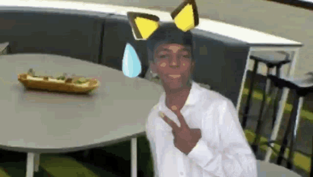 a young man wearing a cat ear headband giving a peace sign