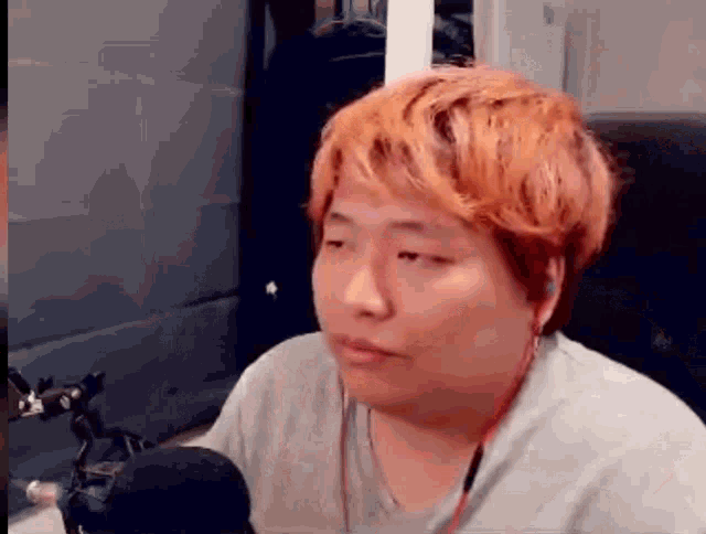 a man with red hair is sitting in front of a microphone and making a funny face .