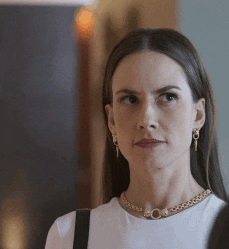 a woman wearing a white shirt and a gold necklace