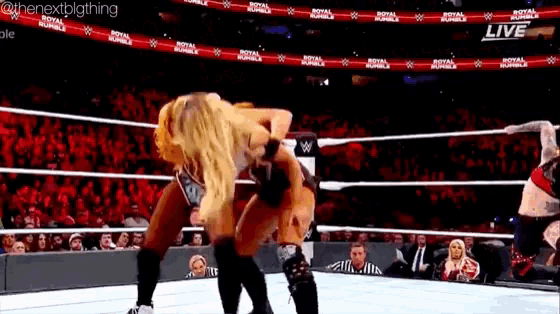 a woman is wrestling another woman in a wrestling ring with a crowd watching .