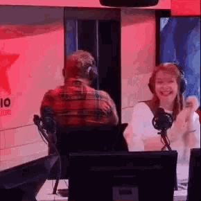 a man and woman are sitting in front of a microphone in a radio studio .