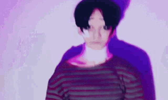 a man in a striped shirt is standing in front of a purple background .