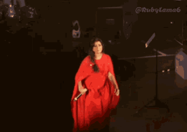 a woman in a long red cape is standing on a stage with rubylama6 written on the bottom right