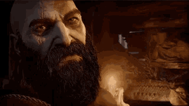a man with a beard is standing in a dark room with a candle in the background .