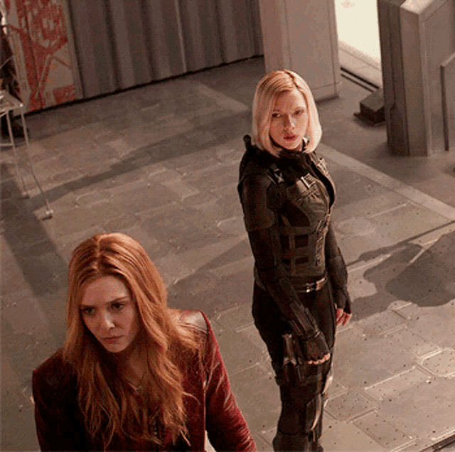 two women are standing next to each other in a room