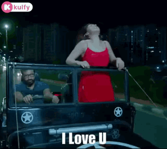 a woman in a red dress is standing in a car with her arms outstretched and says i love u