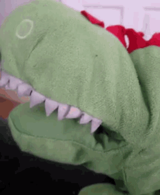 a green stuffed dinosaur with white teeth and a red collar