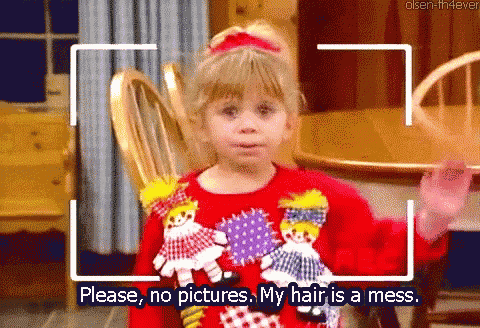 a little girl in a red sweater says please no pictures my hair is a mess .