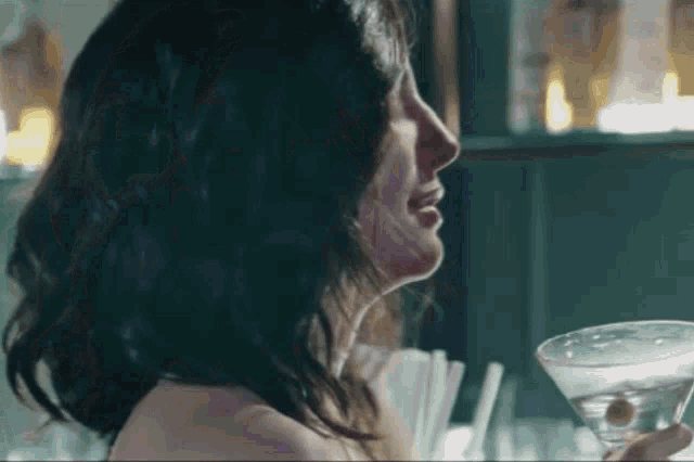 a woman is holding a martini in her hand