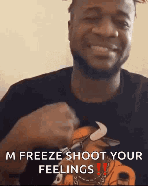 a man in a black shirt with a bull on it is smiling and saying " m freeze shoot your feelings "