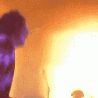 a blurry picture of a person standing in front of a wall with a purple light behind them