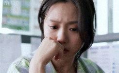 a woman is covering her nose with her hand while sitting at a desk .