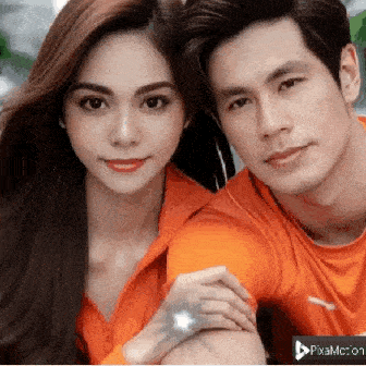 a man and a woman are posing for a picture and the man is wearing an orange shirt