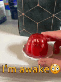 a person is holding a red jelly cup that says " i 'm awake " on it