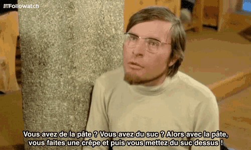 a man wearing glasses and a sweater is talking in french