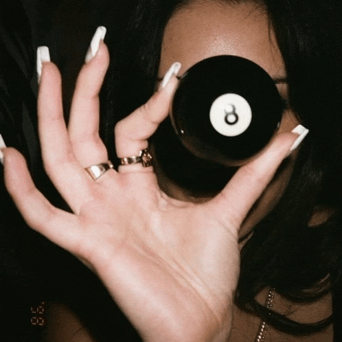 a woman holding a pool ball in front of her eye