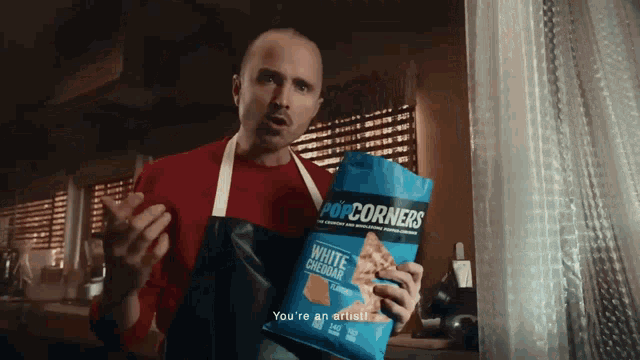 a man holding a bag of popcorn corners white cheddar