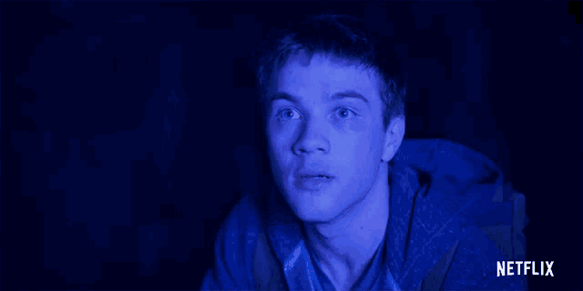 a young man is looking at a screen with a netflix logo behind him