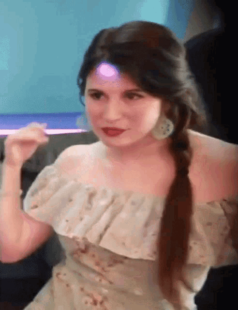 a woman in a white off the shoulder dress has a light shining on her forehead