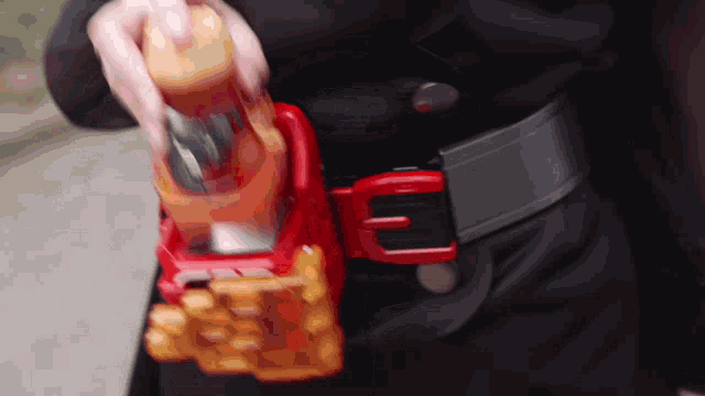 a person is holding a toy gun with a red buckle that has the letter f on it