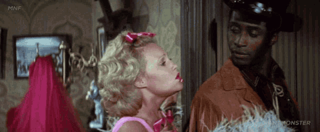 a man and a woman are standing next to each other and the woman is wearing a pink dress .