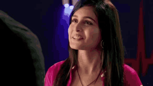a woman in a pink shirt is smiling and looking at a man in a black jacket .