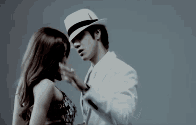 a man in a white suit and hat kisses a woman on the cheek
