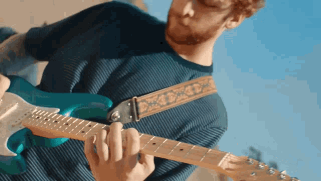 a man with a beard is playing a blue guitar