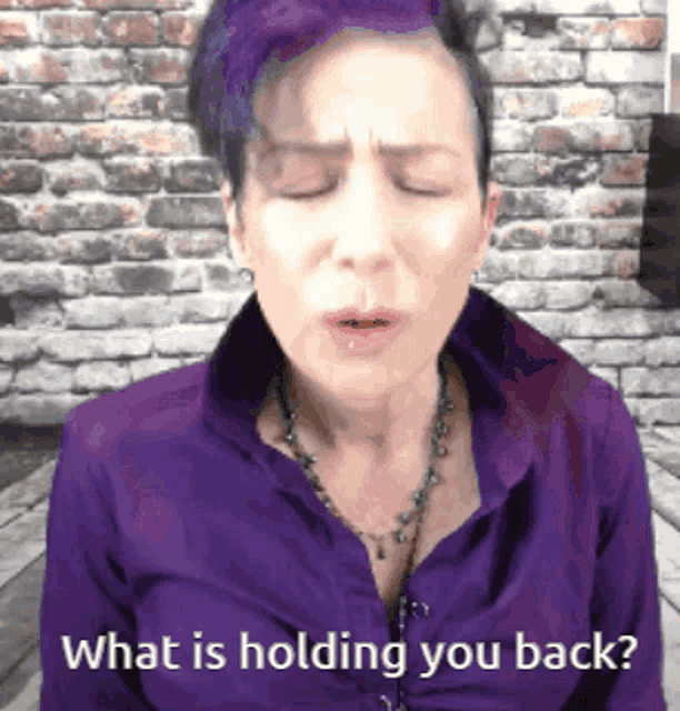 a woman with purple hair and a purple shirt is asking what is holding you back