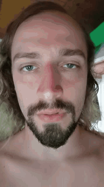 a man with a beard and blue eyes has a red nose