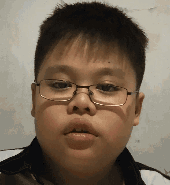 a young boy wearing glasses and a white shirt