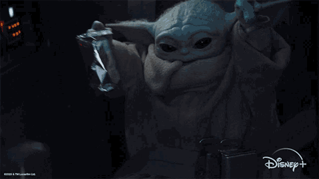 a baby yoda from the mandalorian sits in a car seat with a disney logo in the background