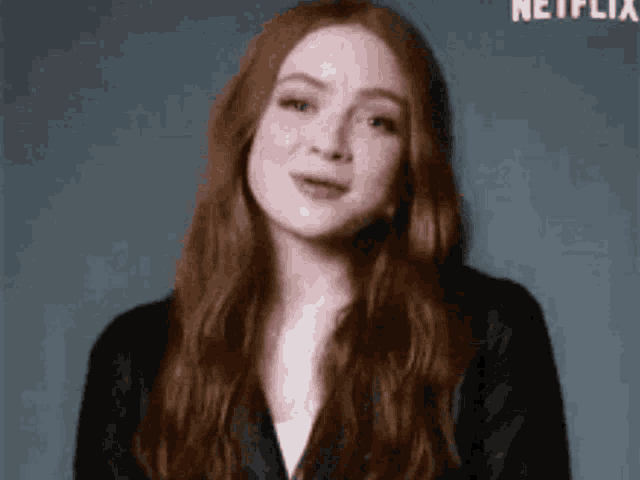 a woman with red hair is wearing a black jacket .