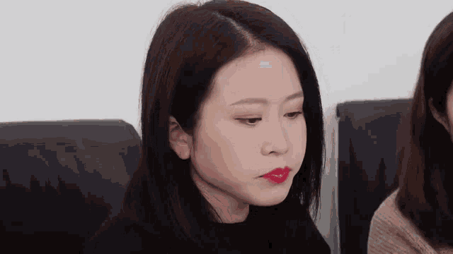 a woman with red lipstick on her lips is sitting next to another woman in a chair .