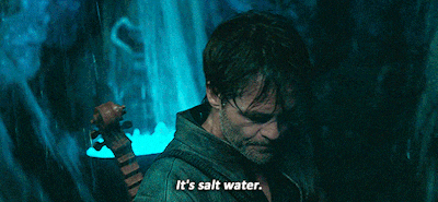 a man holding a violin with the words it 's salt water below him