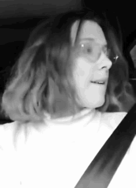 a black and white photo of a woman wearing glasses and a white turtleneck .