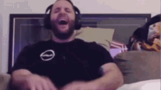 a man wearing headphones is sitting on a couch with his mouth open .