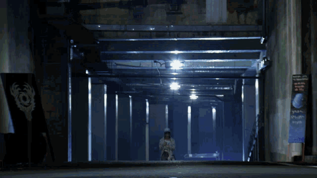 a girl wearing a baseball cap and a floral jacket stands in a dark hallway