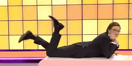 a man in a suit and glasses is laying on his stomach on a pink table .