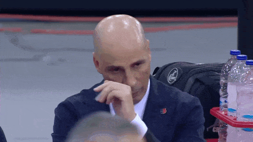 a bald man in a suit with a coca cola logo on his bag