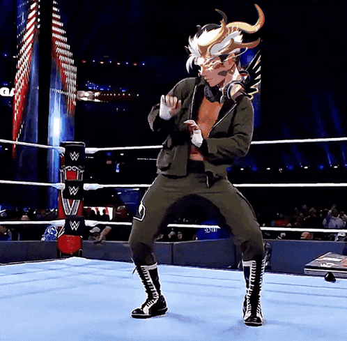 a wrestler is dancing in a wrestling ring with the letters w on the ring