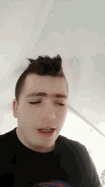 a man with a mohawk on his head is making a funny face with his eyes closed .