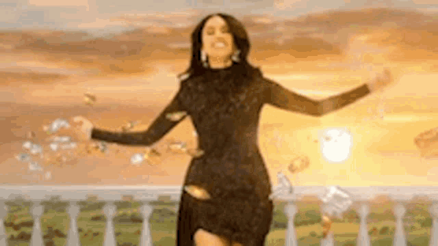 a woman in a black dress is standing on a balcony with her arms outstretched and money falling around her .