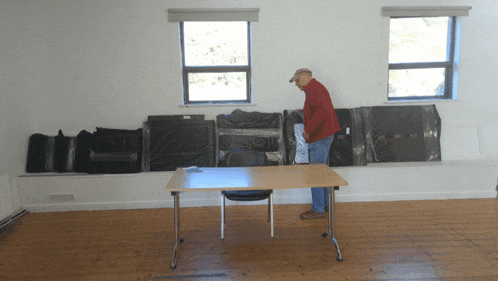 a man in a red jacket is standing in front of a table with boxes wrapped in plastic
