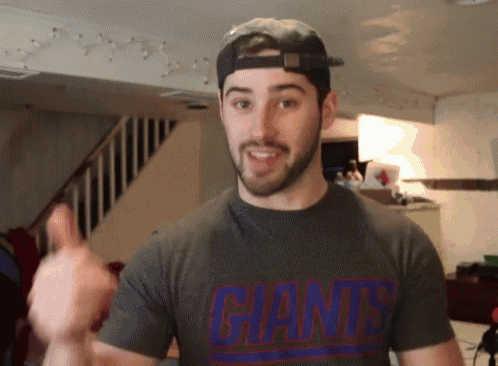 a man wearing a giants t-shirt is giving a thumbs up